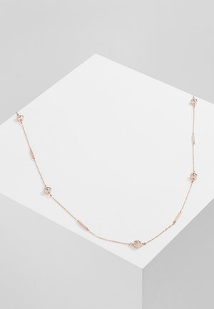 Delikatny naszyjnik z różowego złota z równomiernie rozmieszczonymi małymi okrągłymi i prostokątnymi kryształowymi akcentami, ułożony na białej geometrycznej powierzchni.