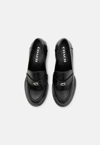 Mocassins en cuir noir avec texture crocodile, détail boucle argentée et logo COACH à l'intérieur de chaque chaussure, vus de dessus sur fond blanc.