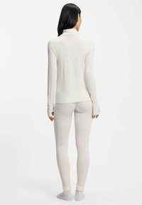 Biały termiczny komplet bielizny bazowej składający się z długiego topu z wysokim kołnierzem oraz dopasowanych legginsów, z fakturowanym wzorem diamentowym.