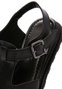 Sandalo nero in pelle con cinturino regolabile a fibbia metallica e suola imbottita, progettato per comfort e una calzata sicura.