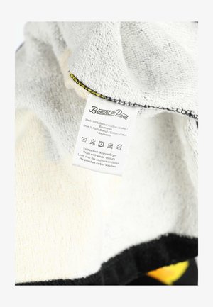 Fabric care label on soft cotton cloth showing washing instructions, material composition (100% cotton), and brand name Blount & Pool.