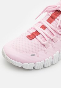 Rosa atletiske sko med en mesh-overdel, der har et struktureret design, gummisål og røde snørebånd for sikkerhed og stil.