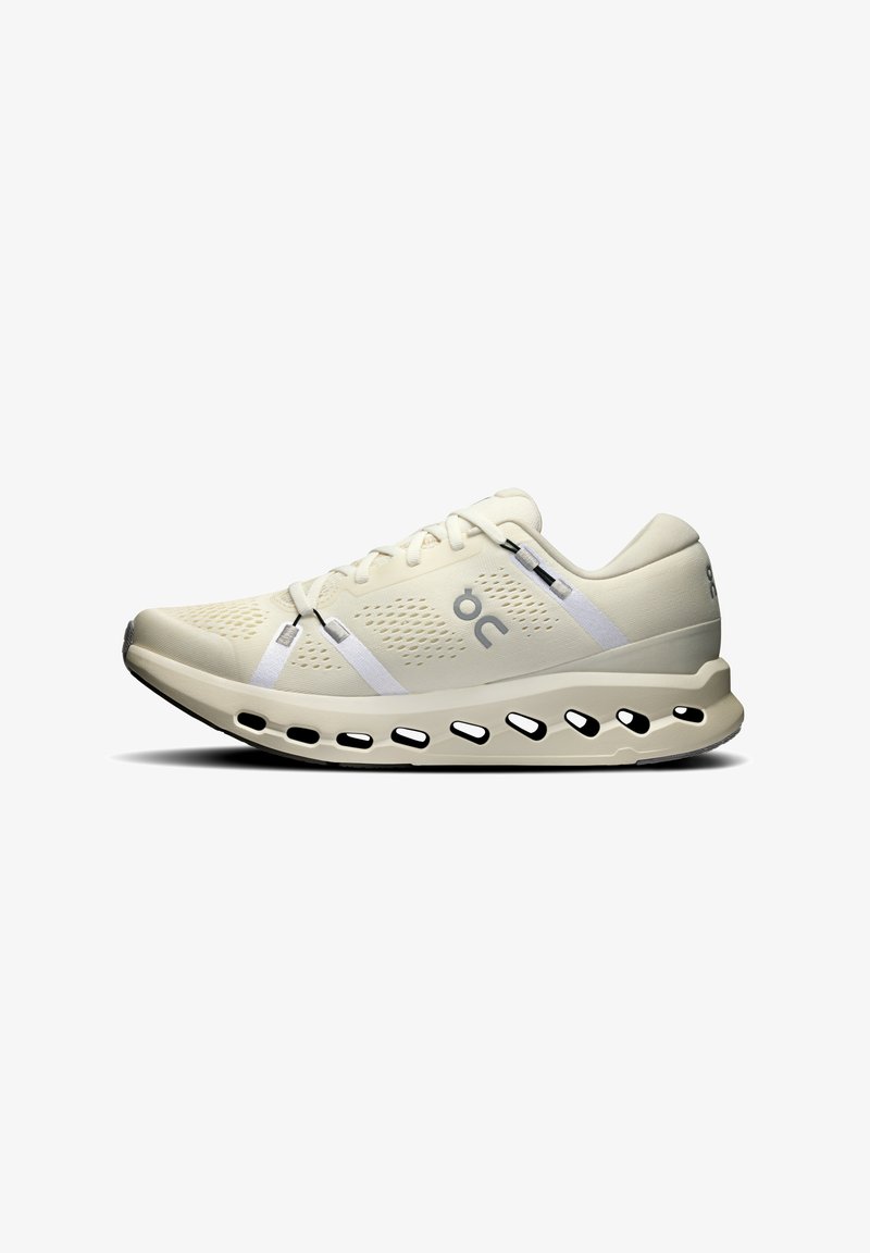 Baskets de course beiges avec une tige respirante, des accents blancs, un design léger et une semelle rembourrée avec des découpes pour la circulation de l'air.