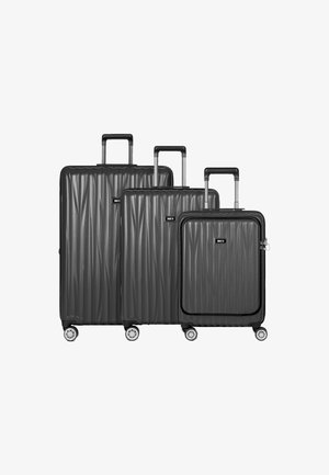 Drie zwarte hardshell koffers van verschillende groottes met een gestructureerd golfpatroon, uitschuifbare handgrepen en spinnerwielen.