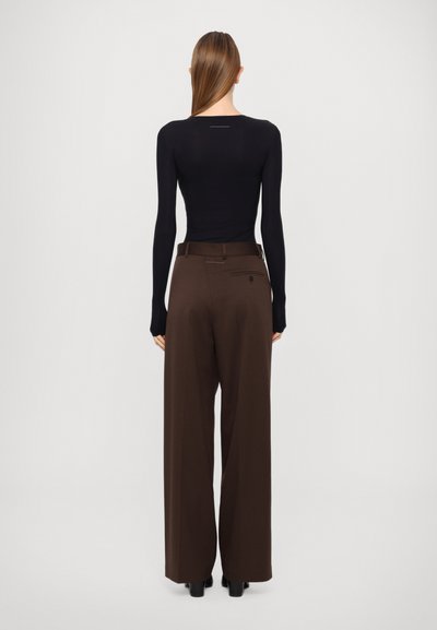 Brown wide-leg pants with a high waist, paired with a fitted black long-sleeve top. Pants feature a back pocket and subtle stitching detail.