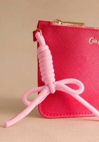 Roza denarnica z teksturo, z zlatim zadrgo in rožnato okrasno vrvico z vozličnim vzorcem ter ujemajočim poudarkom.