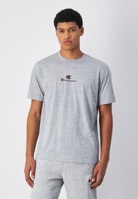 Grijze katoenen t-shirt met een ronde hals, voorzien van een klein rood en blauw Champion-logo op de borst, korte mouwen en een ontspannen pasvorm.