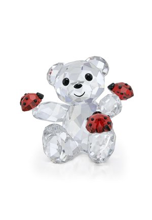 Crystal bear figurine with transparent facets, black eyes, and a smiling mouth; holds two red ladybugs with black spots on its paws.