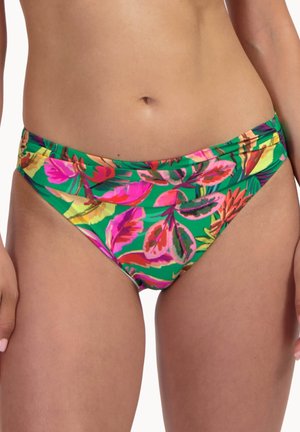 Žena v zelených spodních dílech bikin s jasným růžovým, červeným a oranžovým tropickým květinovým vzorem, oříznutých v polovině trupu a horní části stehen.