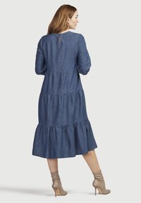 Denim-koskahelma vestido con mangas largas, escote redondo y detalle de ojal en la parte posterior. Presenta un dobladillo con volantes y un corte relajado.