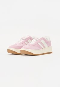 Sneaker in suede rosa con accenti bianchi, lacci tondi e suola in gomma texturizzata. Presenta un design a piattaforma e una morbida fodera interna.
