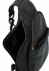Borsa in pelle nera di forma rotonda, caratterizzata da due compartimenti con zip e dettagli in metallo sulla zip. Texture liscia con un interno morbido.