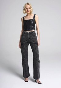Top corto in pelle nera con scollatura quadrata abbinato a pantaloni cargo neri a vita alta, dotati di tasche e taglio dritto.