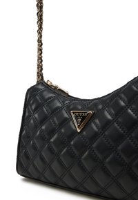 Borsa a tracolla nera trapuntata con catena, con un accentuato logo triangolare in tono oro e chiusura con zip superiore. Texture in pelle liscia.