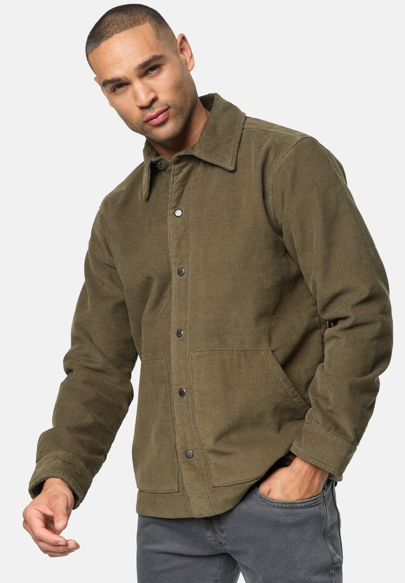 Olijfgroen corduroy jack met een puntkraag, drukknopen aan de voorkant en twee zijzakken. Geweven stof met een ontspannen pasvorm.