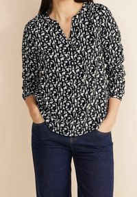 Navy und creme gemusterte Bluse mit V-Ausschnitt, langen Ärmeln und lockerer Passform, aus weichem, leichtem Stoff gefertigt.