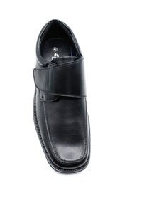 Chaussure en cuir noir avec une finition lisse, dotée d'une sangle en velcro sur le dessus. Embout arrondi et détails de couture subtils le long du bord.