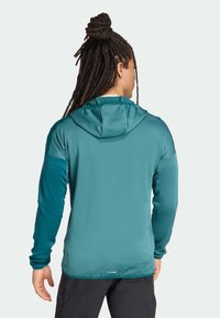 Teal hooded jacket with long sleeves, smooth texture, and contrasting shoulder accents; designed for outdoor activities, featuring a relaxed fit.
