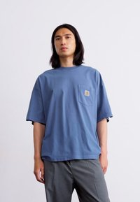 Blå bomulds oversized t-shirt med korte ærmer og en brystlomme, med et lille logomærke på lommen. Enkel design og afslappet pasform.