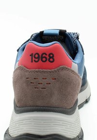 Sneaker blu e grigio con tallone in suede, accenti rossi con "1968", suola texturizzata e tomaia in mesh per la traspirabilità.