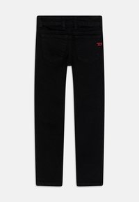 Jeans de mezclilla negra con un corte ajustado, que cuentan con dos bolsillos traseros, un logo de parche en rojo y pasadores para cinturón estándar. Textura de tela suave.