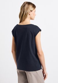 Navy blue lyhythihainen t-paita rentoa mallia, valmistettu pehmeästä kankaasta. Ominaisuuksiin kuuluu pyöreä pääntie ja käännetyt hihansuut. Yksinkertainen muotoilu.