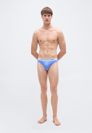 Ljusblå herrunderbyxor med en vit midjeresår med texten "POLO RALPH LAUREN". Mjukt tyg och åtsittande passform. Modellen står barfota och blickar framåt.