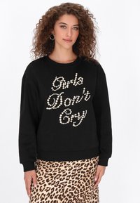 Fekete pulóver fehér gyöngydíszít�éssel, amely a "Girls Don't Cry" feliratot formázza. Hosszú ujjakkal, bordázott mandzsettákkal és szegéllyel.