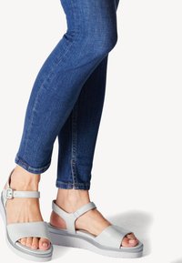 Harmaat platform-sandaalit avoimella varpaalla ja nilkkahihnalla, joissa on sileä pinta ja minimalistinen muotoilu. Yhdistetty tummansinihin slim fit -farkkuihin.