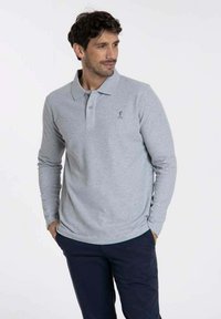 Polo à manches longues en coton gris clair, avec un col et un petit logo sur la poitrine gauche. Coupe ajustée et texture douce.