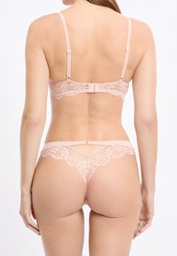 Spitzen-BH- und Tangasetz in Hellrosa. Mit zarten Blumenmustern, verstellbaren Trägern und einem Hakenverschluss auf der Rückseite. Glatte Textur.