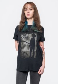 Black cotton t-shirt featuring a graphic design of a silhouette with a guitar, text "THE CURE" and "BOYS DON’T CRY" in bold lettering.