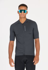 Kurzarmpullover für Radfahrer in Dunkelgrau, mit einem Reißverschluss auf der Vorderseite, schlanker Passform und reflektierendem Logo. Getragen mit schwarzen gepolsterten Shorts.