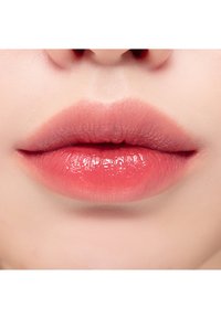 Lähikuvassa huulet, joissa on pehmeiden vaaleanpunaisen sävyjen gradientti ja kiiltävä pinta. Sujuva rakenne ja luonnollinen muoto, ilman näkyviä koristeita.