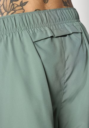 Zielone krótkie spodenki z elastycznym pasem i tylną kieszenią. Materiał ma gładką fakturę z lekkim połyskiem.
