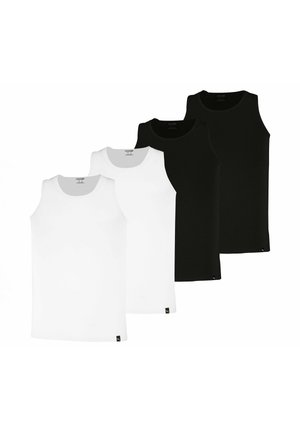 Mann mit kurzen lockigen Haaren, der ein schwarzes ärmelloses Shirt und graue Boxershorts trägt, steht vor einem weißen Hintergrund.