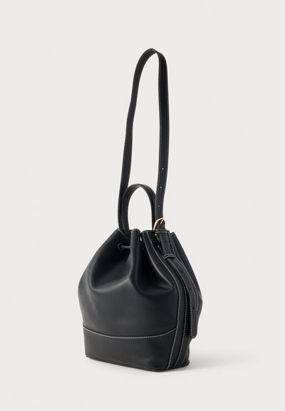 Sort læder buckettaske med snørelukning, lang skulderrem og kontrasterende hvide syninger. Rund bund og glat tekstur.
