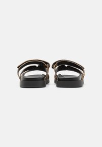 Brown leather sandals with adjustable straps, a black rubber sole, and minimalistic design. Open back and toe area for breathability.