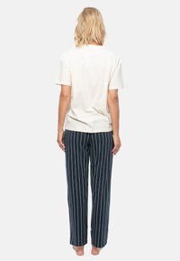 Ljusgrå kortärmad t-shirt i kombination med marinblå byxor med vita vertikala ränder; tyget verkar slätt och lätt.