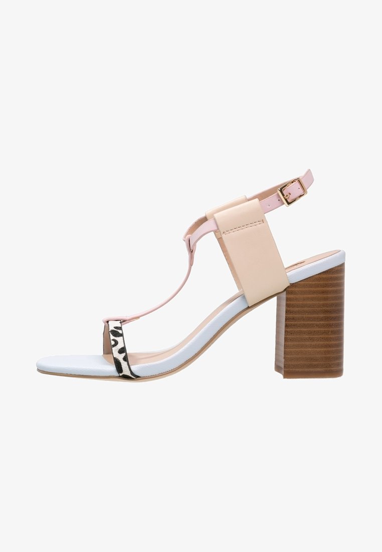 Sandale à brides T beige et rose avec une bride d'orteil à imprimé léopard, semelle blanche, et talon bloc en bois épais avec boucle à la cheville.