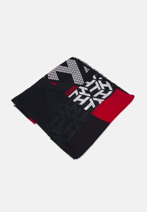 Złożony czarny szalik z geometrycznymi białymi i czerwonymi wzorami oraz czerwonym jednolitym blokiem, prezentowany na jasnoszarym tle.