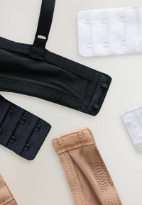 Melna, bēša un balta krūštura siksnas un āķi ar dažādiem tekstūru un platumu variantiem. Melnais siksna ietver regulējamu aparatūru.