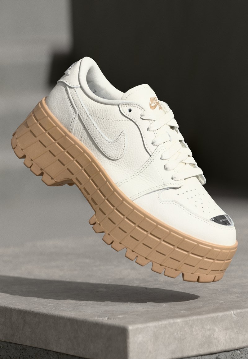 Hvide lædersneakers med en klodset beige ydersål, som har en perforeret tå, snørebånd og diskret branding på tungen.