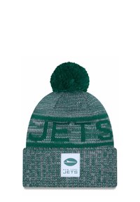 Grüner Strickmütze mit einem strukturierten Muster, ausgestattet mit einem flauschigen Pompon oben und einem Umschlag, der das Logo und den Namen der New York Jets zeigt.