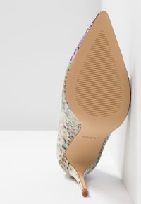 Chaussure à talon aigu multi-couleurs avec un bout pointu, comportant un dessus en tissu texturé et une semelle lisse de couleur marron clair avec des rainures.