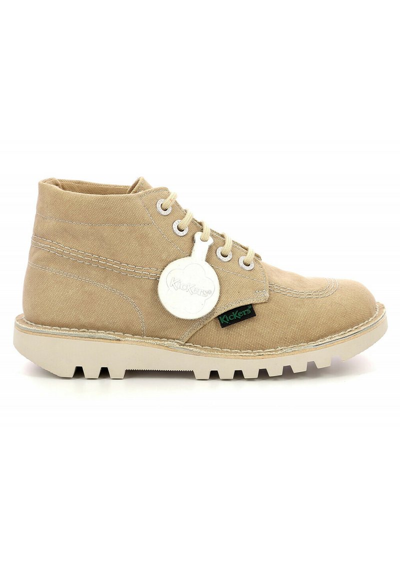 Botín de lona beige hasta el tobillo con cordones blancos, suela de goma y etiqueta decorativa. Presenta un contraste de costuras y una etiqueta de logo verde en el lateral.