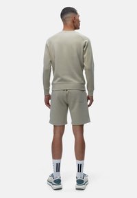 Light grey sweatshirt and shorts set, cotton blend material, textured finish, relaxed fit, featuring a back pocket on shorts and ribbed cuffs.