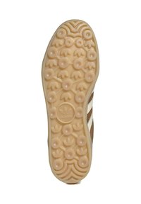 Suola di gomma marrone con motivi a grip circolari, superficie texturizzata e strisce bianche; presenta il logo Adidas al centro.