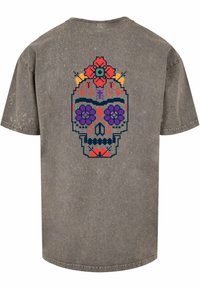 Grå bomulds t-shirt med et farverigt pixeleret kranie-design på ryggen, omgivet af blomsterdetaljer i rød og lilla.