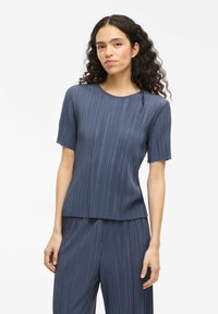 Top plissettato blu con maniche corte e colletto rotondo, realizzato in un materiale liscio. Caratterizzato da una texture verticale e una vestibilità comoda.